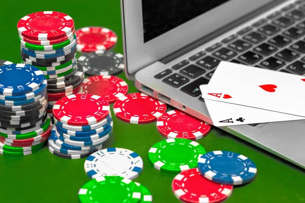 Blockchain per poker: computer portatile con sopra due carte da poker (un asso di cuori e uno di fiori). A sinistra delle fiches 